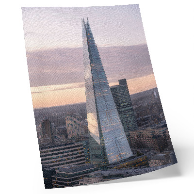 Wandposter Ein Wolkenkratzer im Sonnenuntergang, der einen Kontrast zur Stadt bildet.